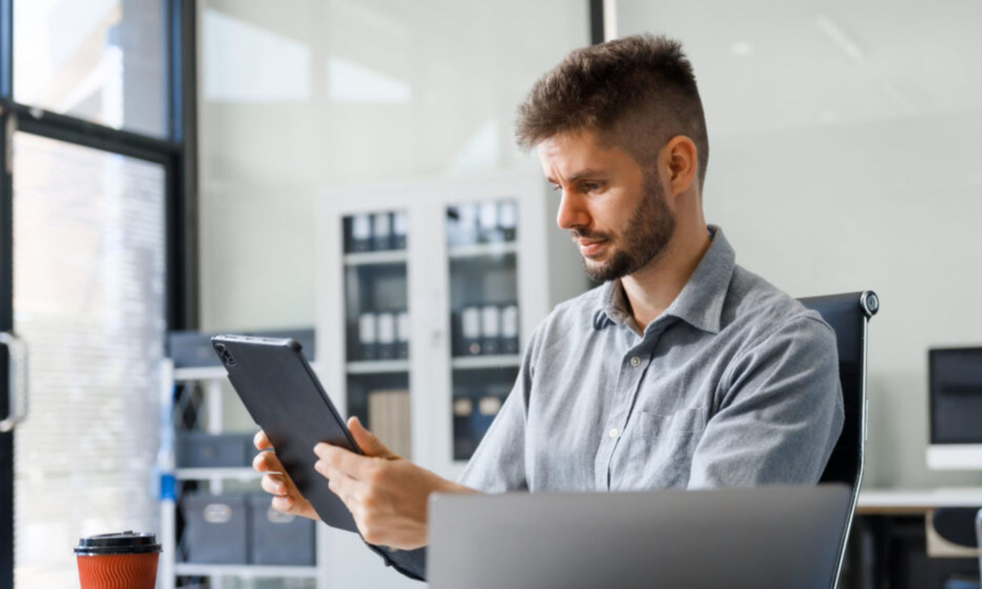 Business professional reviewing financial management software on a digital tablet in a modern office setting.
