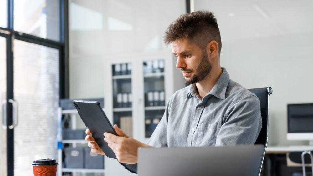 Business professional reviewing financial management software on a digital tablet in a modern office setting.