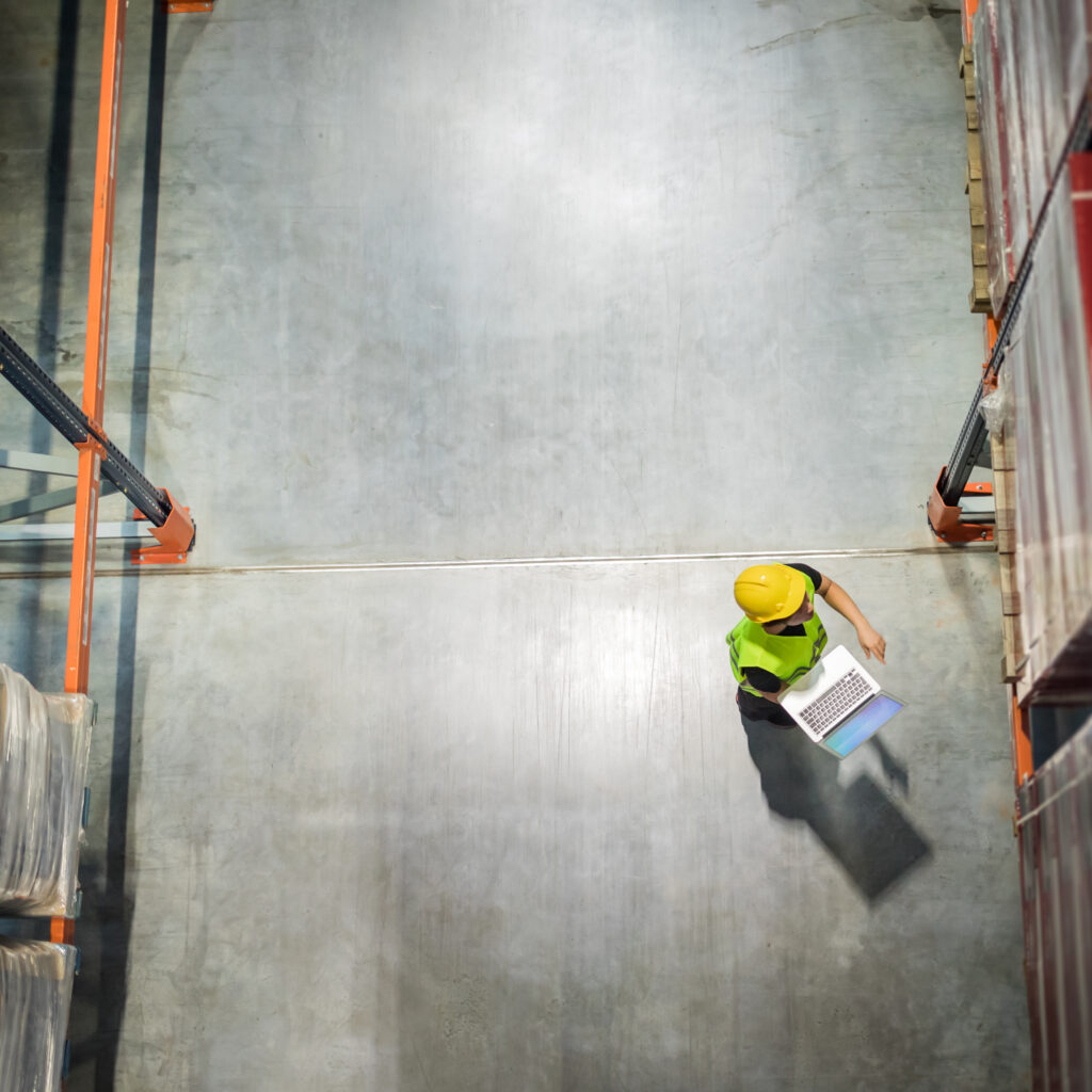 Warehouse worker using a laptop to manage inventory and processes, representing Sage 200 implementation for distribution and operations management.