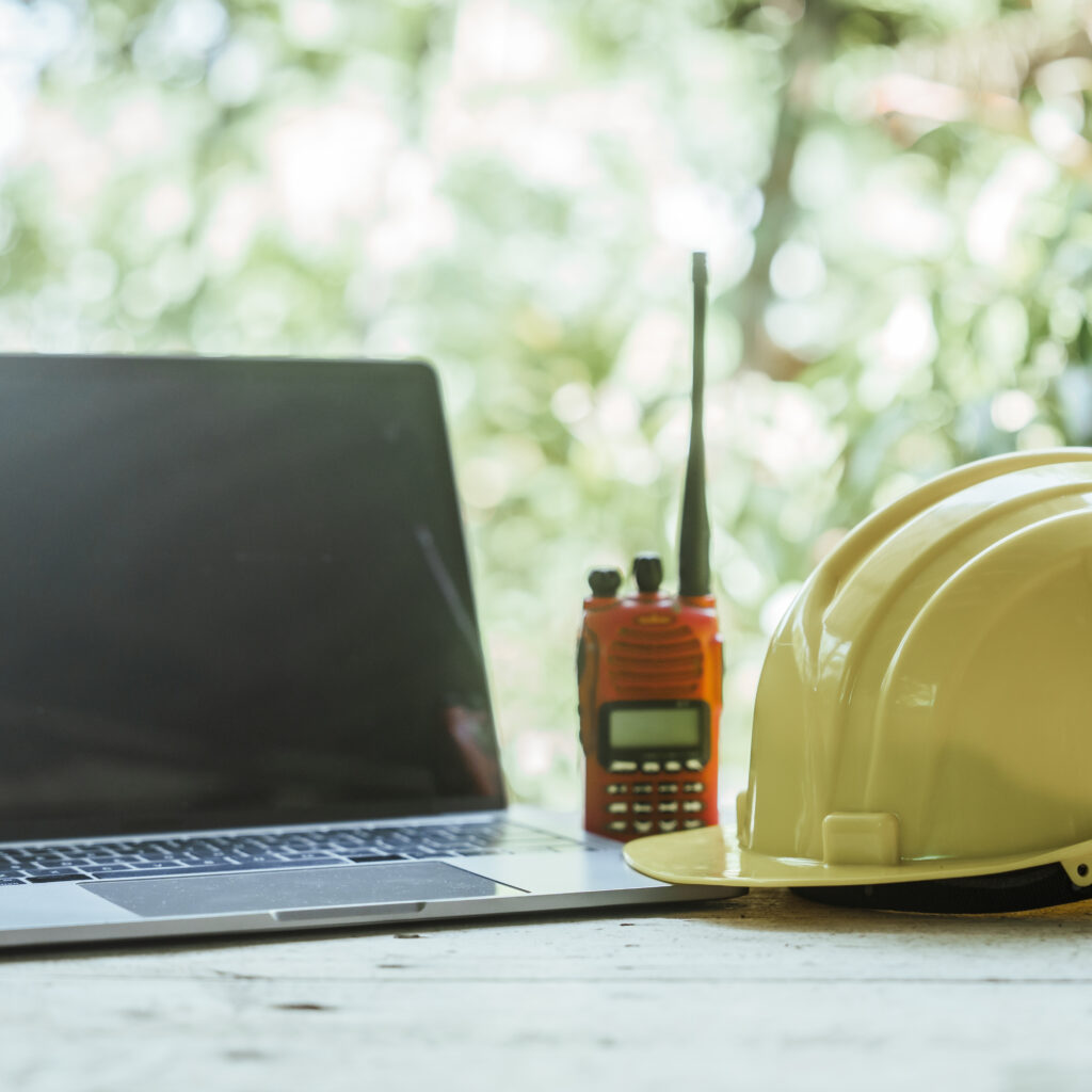 A hard hat beside a laptop symbolising the connection between construction site operations and modern financial management with Sage Intacct.