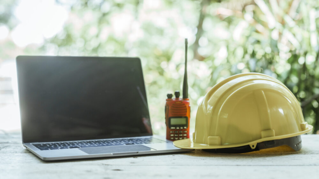 A hard hat beside a laptop symbolising the connection between construction site operations and modern financial management with Sage Intacct.