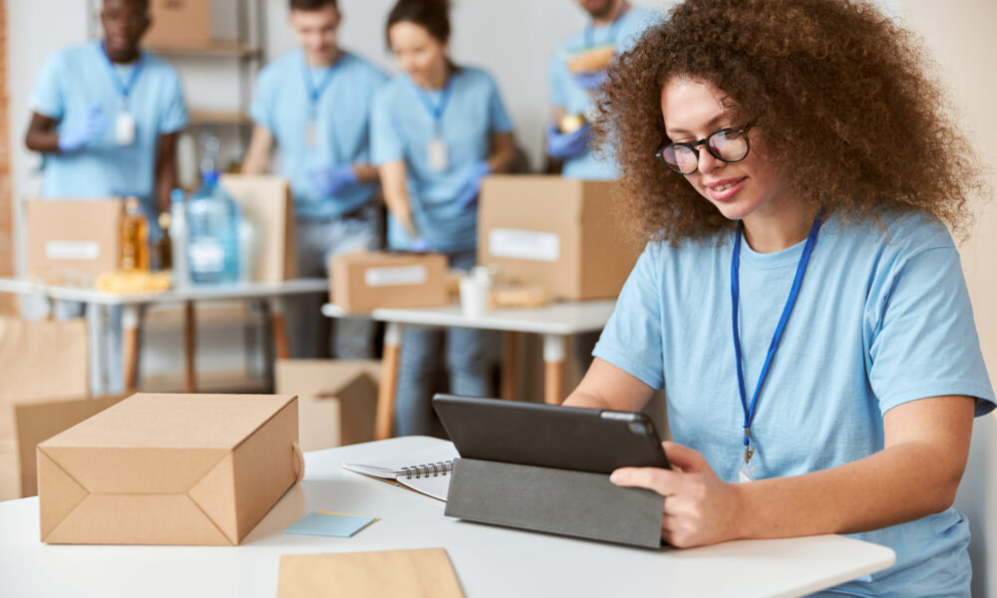 Young woman volunteer in blue uniform holding a laptop for nonprofit finance work in Ireland