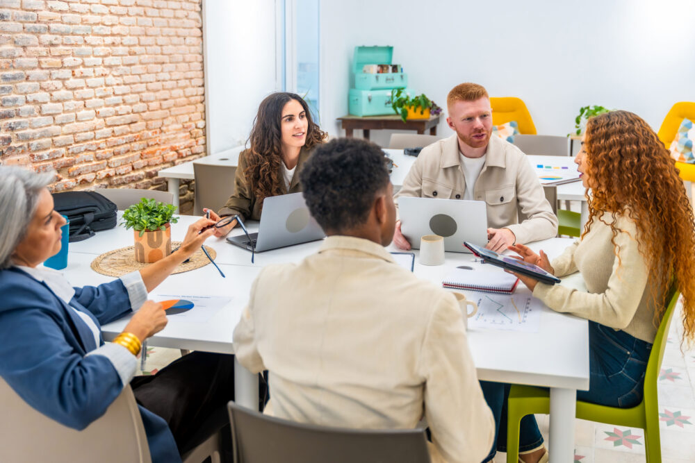 Diverse startup team collaborating in office using Sage Ireland charity accounting software dashboards
