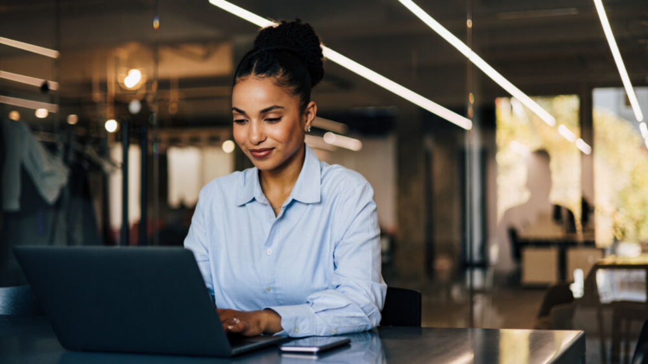 Businesswoman working on laptop in retail shop using best AI accounting software like Sage Intacct