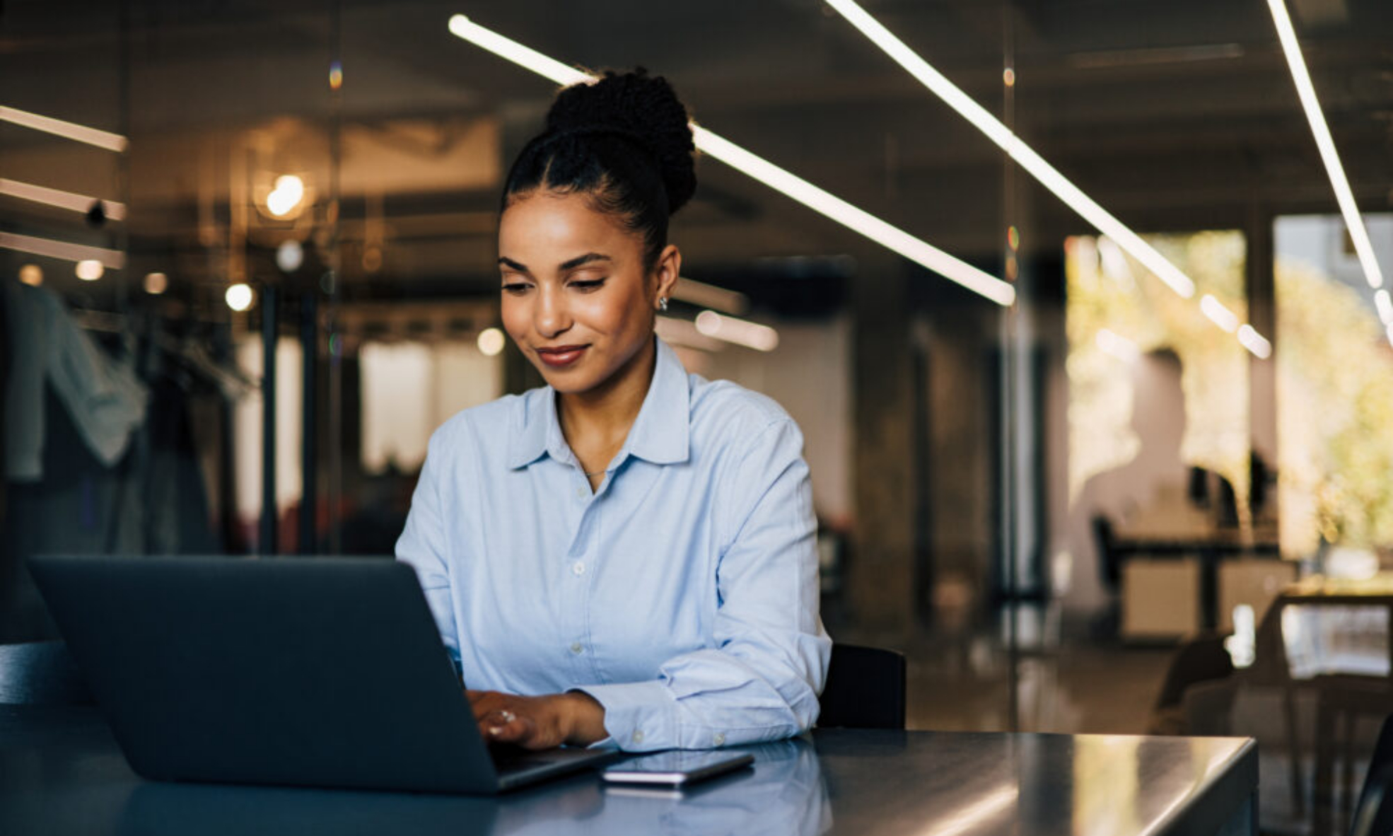 Businesswoman working on laptop in retail shop using best AI accounting software like Sage Intacct
