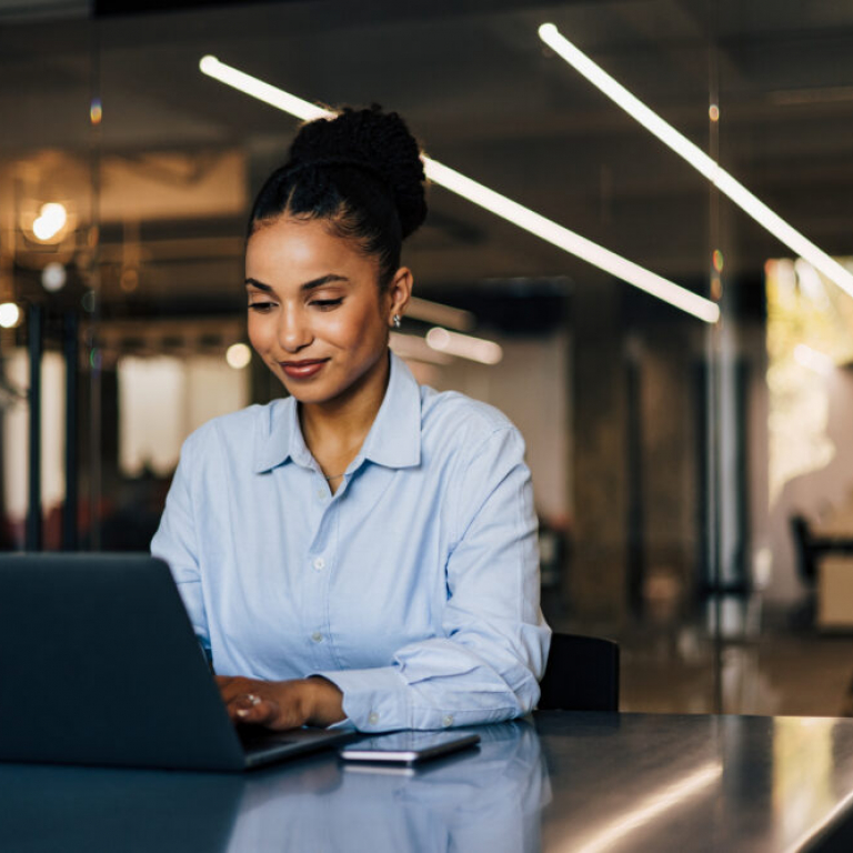 Businesswoman working on laptop in retail shop using best AI accounting software like Sage Intacct