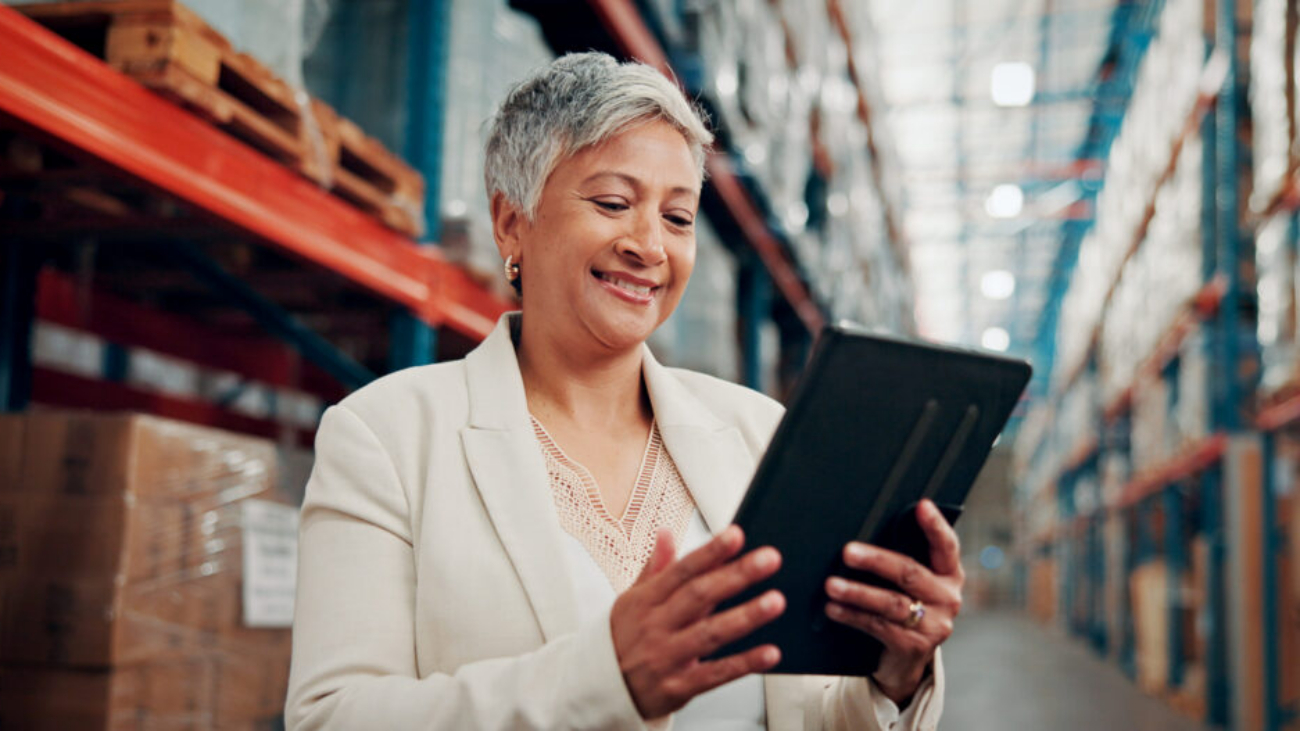 Warehouse employee using a tablet to access AI-powered financial management software for real-time business insights.