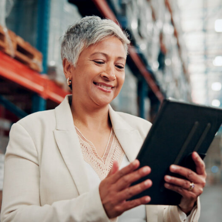 Warehouse employee using a tablet to access AI-powered financial management software for real-time business insights.